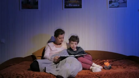 Mother and son read bedtime stories. Covered with a plaid. Flying shadows. Stock Footage 131043207