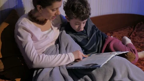 Mother and son read bedtime stories. Covered with a plaid. Tells stories. Stock Footage 131043219