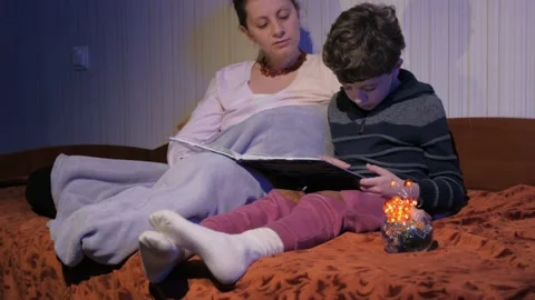 Mother and son read bedtime stories. Covered with a plaid. Tells stories. Stock Footage 131043223