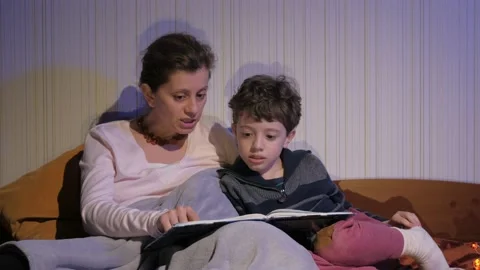 Mother and son read bedtime stories. Covered with a plaid. Tells stories. Stock Footage 131043231
