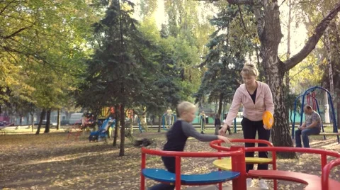 Mother and son riding on the carousel. In the background, drive cars. Stock-Footage 68175366