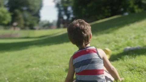 A mother and son roll down a grassy hill while playing at the park Video stock 143629472