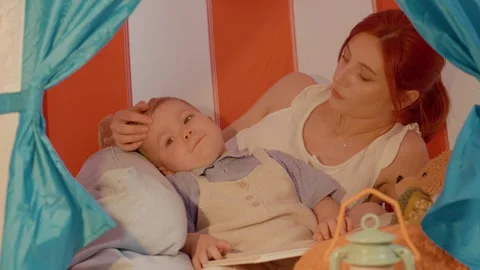 Mother and son share a cozy moment in a tent with bedtime stories Stock Footage 329227004
