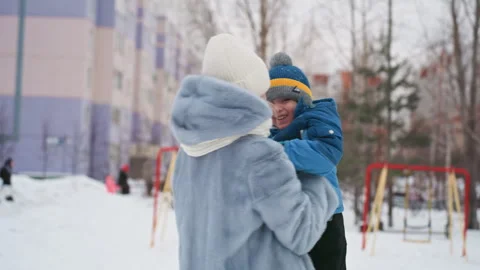 Mother and son share joyful embrace. Loving mother holds son in cheerful winter Stock Footage 345139764