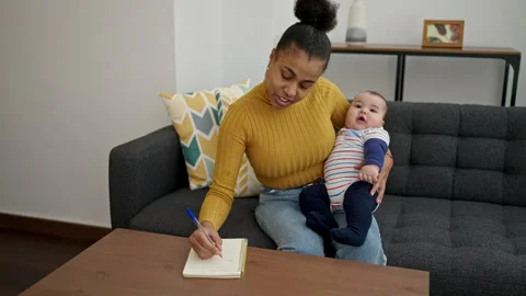 Mother and son sitting on sofa writing notes at home Video stock 245089192
