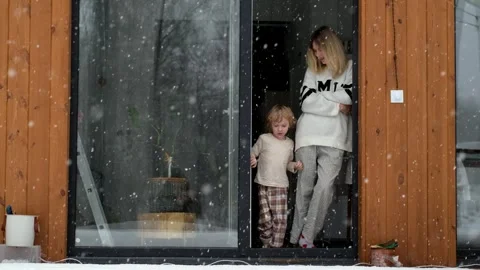 Mother and son standing at open door to terrace in snowy weather Stock Footage 303718191