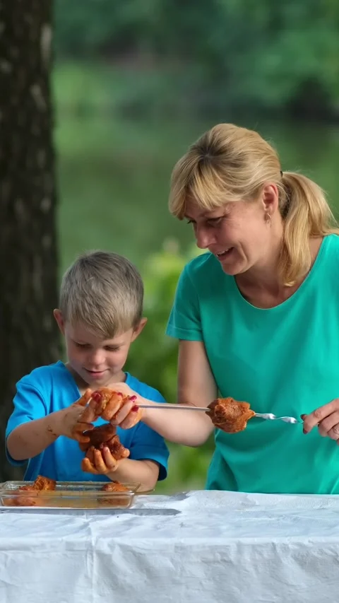 Mother and son stringing marinated meat on skewers. A family picnic in the .. Stock Footage 305847042