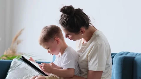 Mother and son with tablet at home. Mother showing media content on line to her Stock Footage 158181563