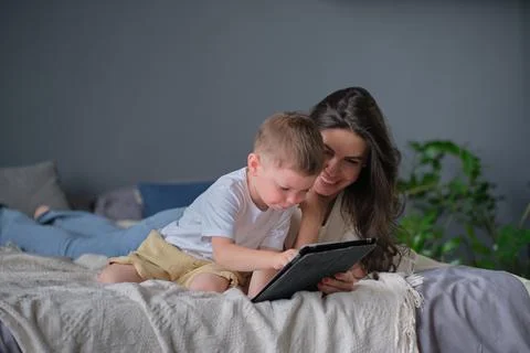 Mother and son with tablet at home. Mother showing media content on line to her Stock Photos