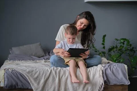 Mother and son with tablet at home. Mother showing media content on line to her Stock Photos