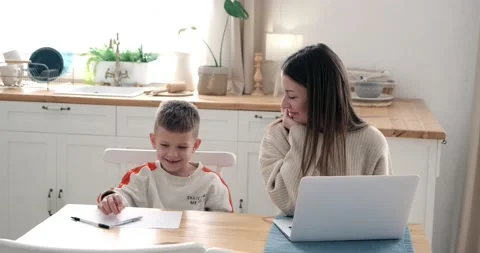 Mother and son talking while using laptop and drawing on paper at home Stock Footage 239453980