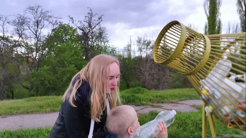 Mother and son throw the plastic bottle into the plastic collection container. R Video stock 153525713