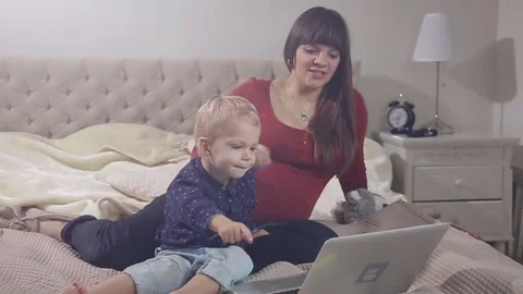 Mother and son is using laptop on a bad. FULL HD. flare Stock Footage 73971859