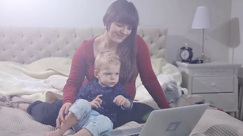 Mother and son is using laptop on a bad. FULL HD. flare SLOW MOTION Stock Footage 73972336