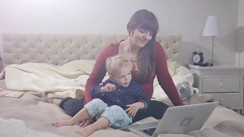 Mother and son is using laptop on a bad. FULL HD. flare Stock Footage 73972624
