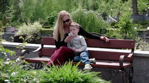 Mother and Son Using Mobile Phone in Park Stock Footage 62783048