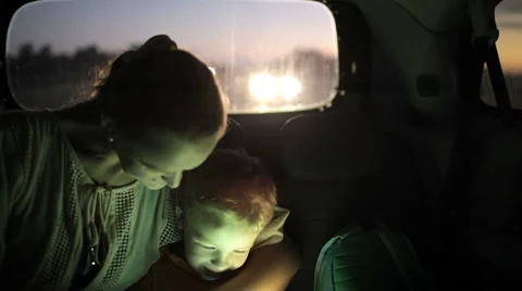 Mother and son using touch pad in car at night Stock Footage