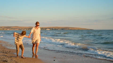 Mother and son walking on sandy beach at sunset Stock Footage 330119072