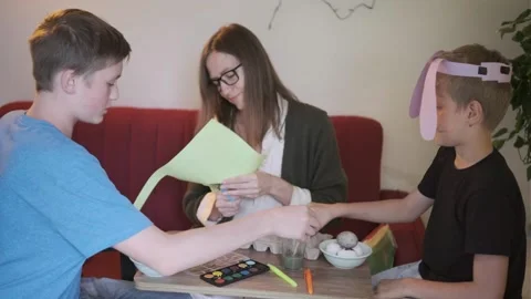 Mother and sons painting Easter eggs at table, happy family spending festive Stock Footage 336668895