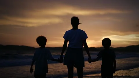 Mother and sons walking on the ocean beach under Sunset Stock Footage 252831853