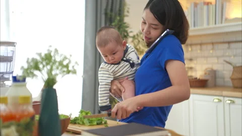Mother and tiny child in the kitchen preparing dinner Stock Footage 288164360