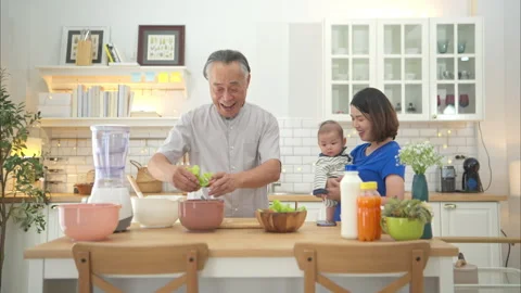 Mother and tiny child in the kitchen preparing dinner with grandfather Stock Footage 288168915