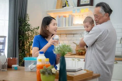 Mother and tiny child in the kitchen preparing dinner with grandfather Mot... Stock Photos