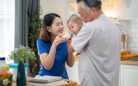 Mother and tiny child in the kitchen preparing dinner with grandfather Mot... 스톡 사진