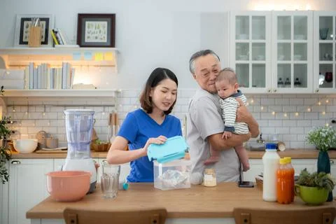 Mother and tiny child in the kitchen preparing dinner with grandfather Mot... 스톡 사진