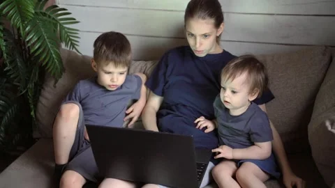 Mother and two children focused on laptop screen while sitting on couch, warm Stock Footage 331127357