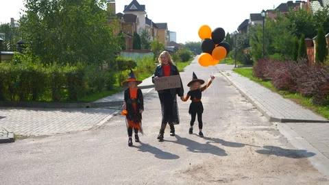 Mother and two daughters trick or treat in the village at Halloween holiday. Stock Footage 182113018