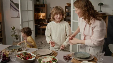 Mother and Two Sons Serving Salad and Hugging at Dinner Table Stock Footage 340332455