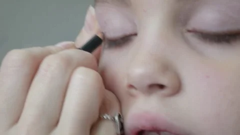 Mother applying eye shadows on the lips of her daughter Stock Footage 84630673
