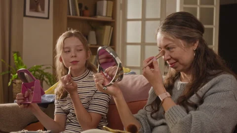 Mother Applying Powder to Face while Teaching Daughter Beauty Routine at Home Stock Footage 334333314