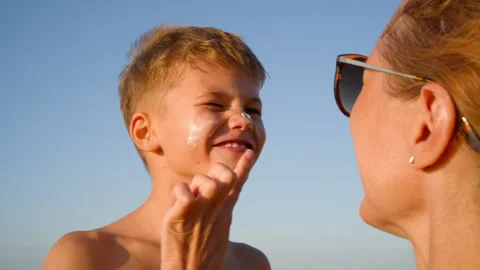 Mother Applying Sunscreen to Her Son's Face Stock Footage 317745845