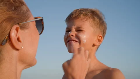 Mother applying sunscreen on son face at the beach Stock Footage 326640920