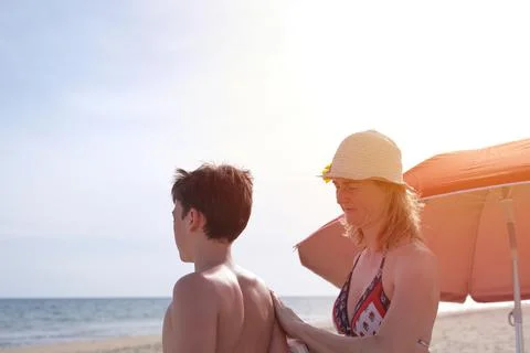 Mother applying sunscreen on son Stock Photos
