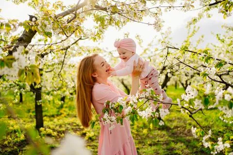 Mother with baby in arms in flowering garden. surgery for child with cleft lip. Stock Photos