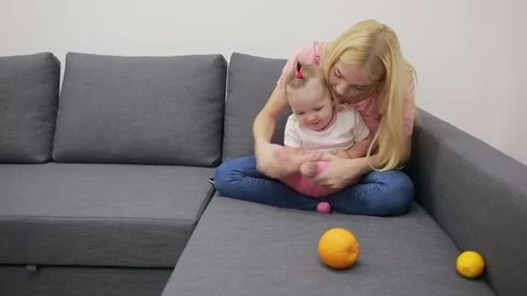 Mother with baby playing on couch Stock Footage 69756777