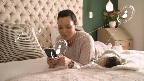 Mother on bed tapping smartphone and generating technology avatar network while Stock Footage 333529035