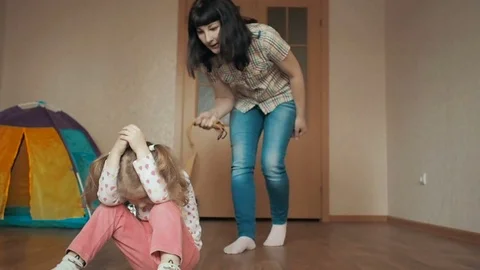 Mother with a belt in her hands scolds her daughter. A small child is afraid Stock Footage