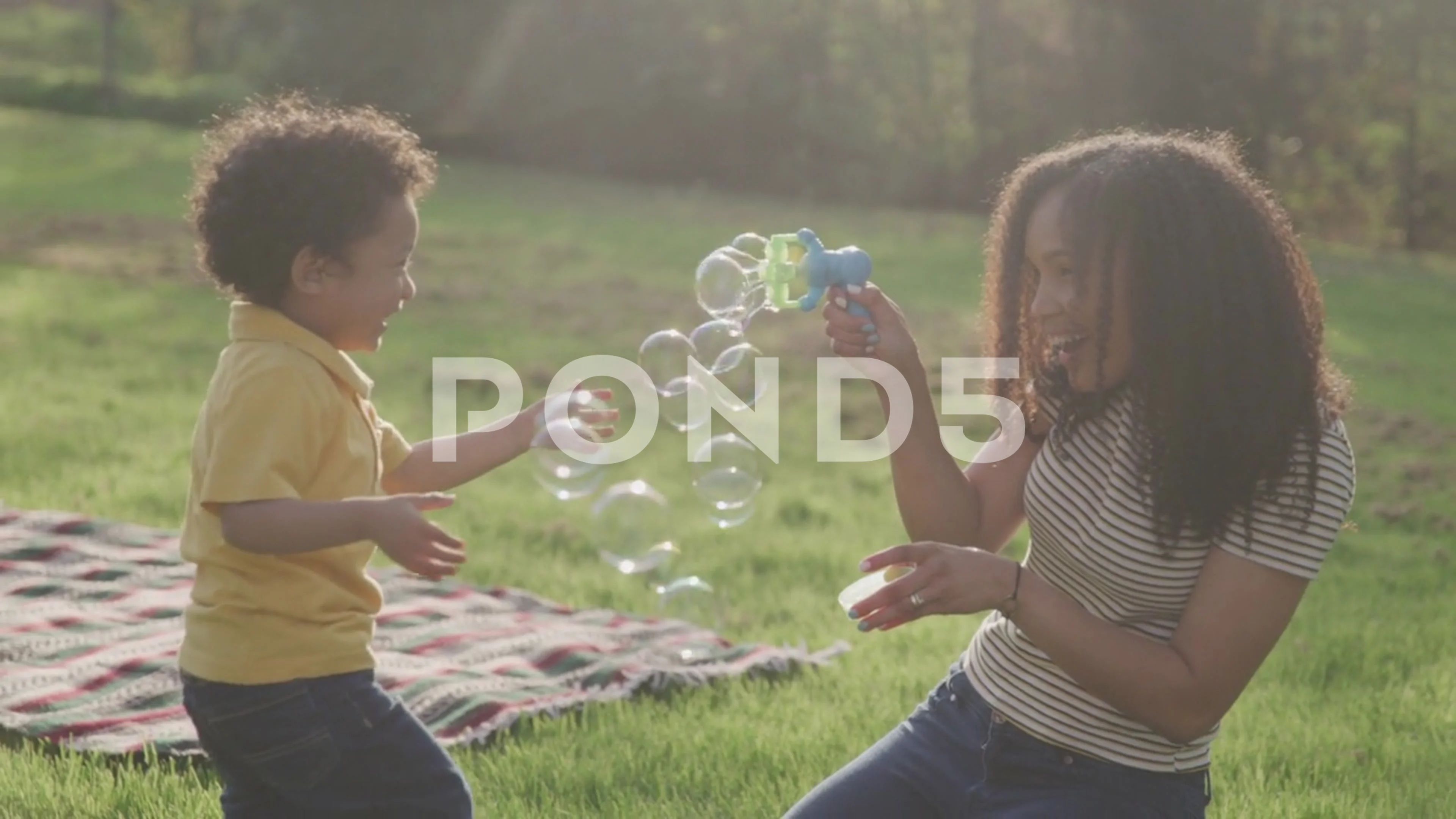 Mother Blowing Bubbles at Her Son at the Park