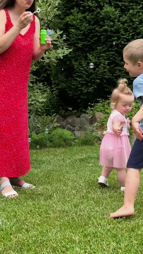 Mother Blowing Soap Bubbles While Children Play Outdoors Stock Footage 339391335