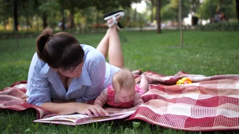Mother bonding with baby while reading in park Video stock 227876131