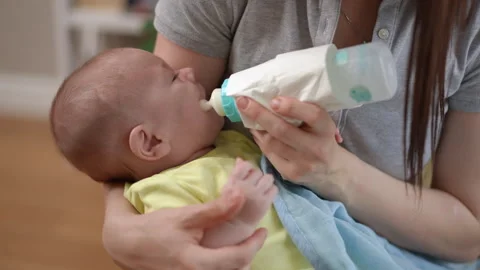 Mother bottle feeding her crying newborn baby at home 스톡 동영상 338342002