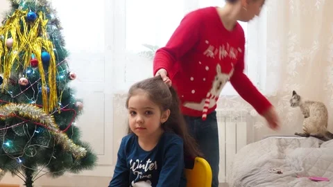 Mother braids her daughter's hair. Morning Christmas  New Year's decor Stock Footage 249242540