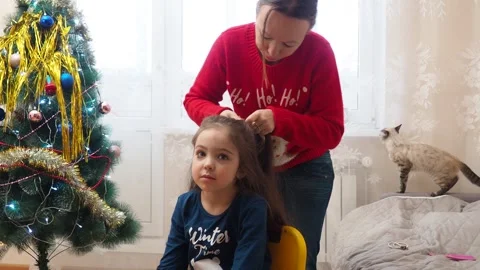 Mother braids her daughter's hair. Morning Christmas  New Year's decor Видео 249242541