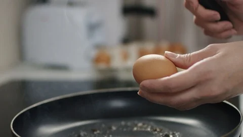 Mother breaks the third egg for scrambled eggs to prapared pan Stock Footage 108114757