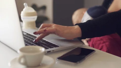 Mother breastfeeds her child while using her laptop Stock Footage 70666245