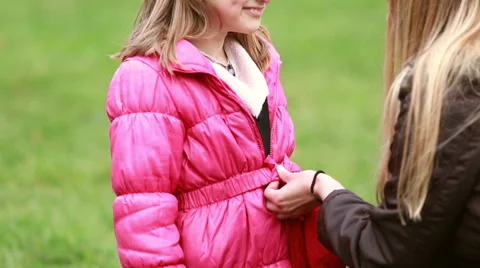 Mother buttoning daughter's jacket Stock Footage 59554605